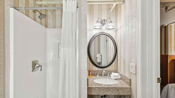 A bathroom with a shower, a sink with a mirror, and a towel rack. - Hotel Seward (Seward)