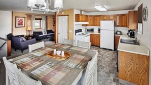 A compact kitchen with wooden cabinets, a microwave, stove, and a refrigerator. - Hotel Seward (Seward)