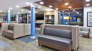 Un espace de détente moderne, doté de différents types de sièges, d’un grand téléviseur à écran plat et d’un tapis à motifs.