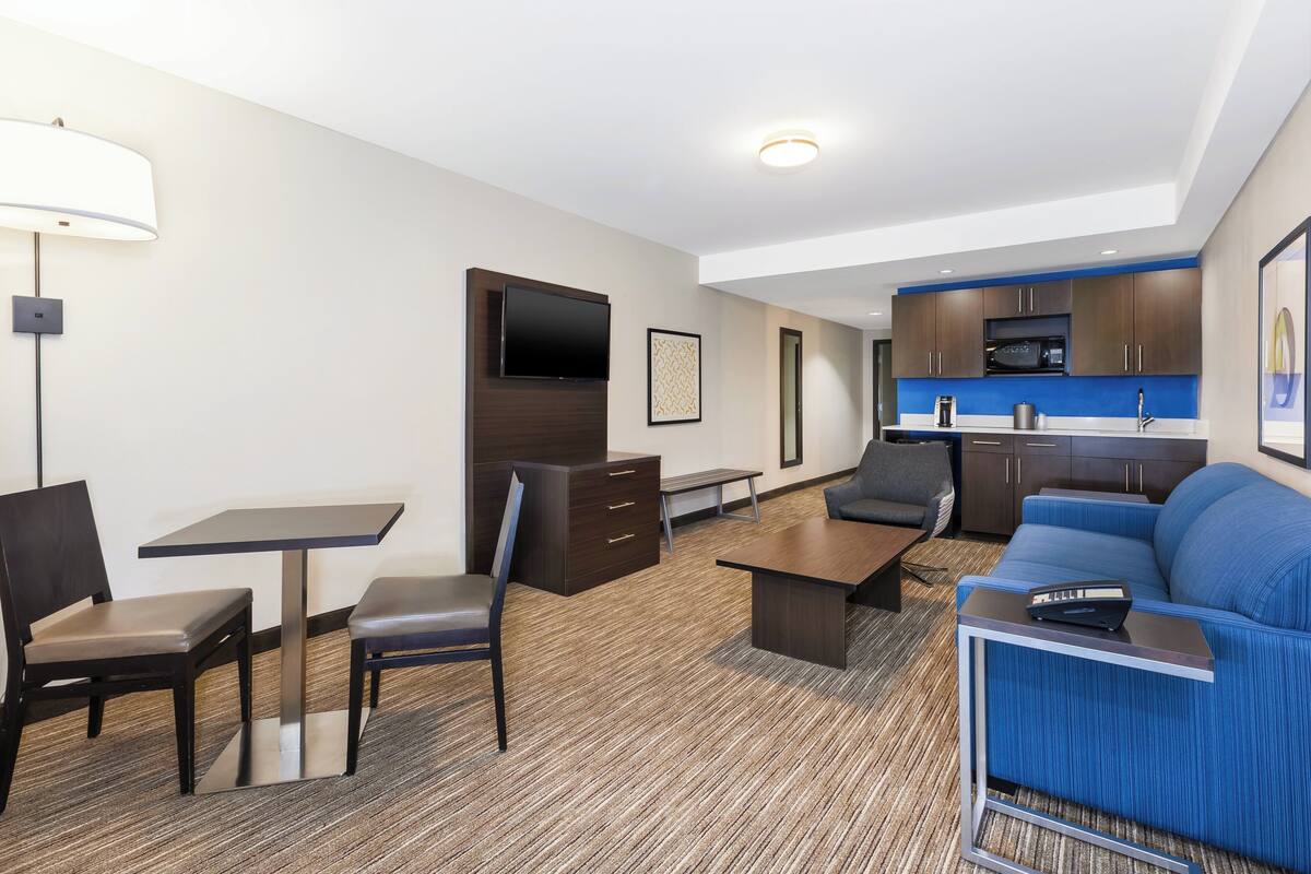Une chambre d’hôtel moderne dotée d’un coin repas, d’une kitchenette et d’un espace salon.