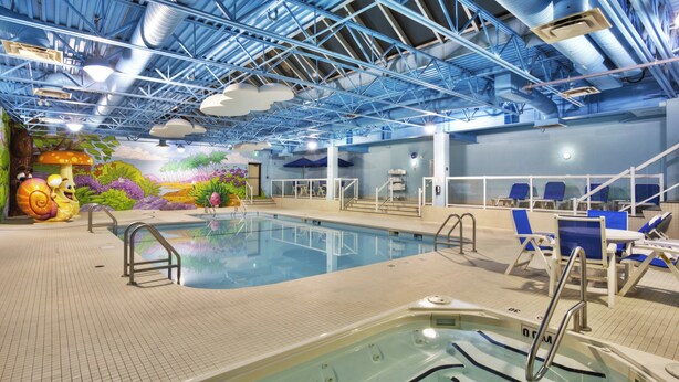 Une piscine intérieure agrémentée d’une fresque murale, d’un espace de détente et d’un jacuzzi.