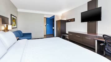 Una habitación de hotel con una cama grande, un escritorio, una silla, un televisor y un armario.