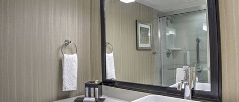 Une salle de bain moderne avec un grand miroir, un lavabo blanc et un porte-serviettes.