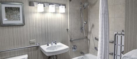 A modern bathroom with a toilet, sink, bathtub, and shower.