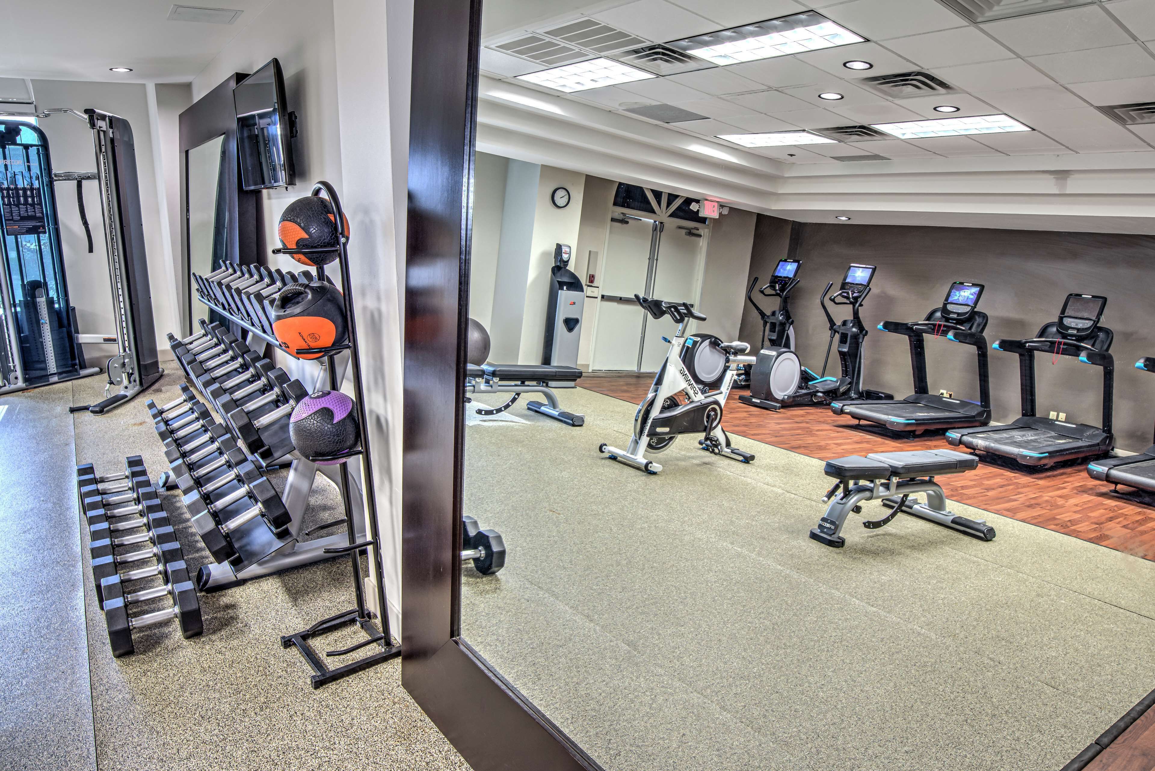 Une salle de sport équipée de divers appareils d’exercice, notamment des tapis de course, des vélos elliptiques et des poids libres.