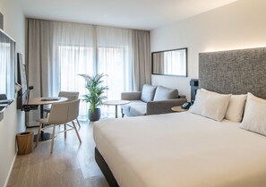 Une chambre d’hôtel moderne équipée d’un grand lit, d’un canapé, d’une table à manger et d’un téléviseur.