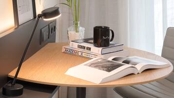 Un espacio de trabajo ordenado con escritorio, lámpara, planta en maceta, taza y libros.