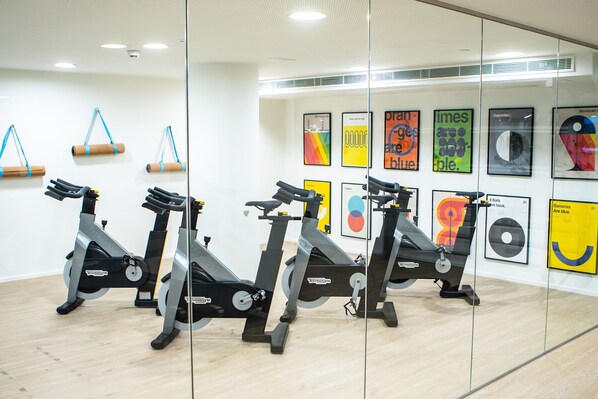 Un gimnasio con bicicletas estáticas, pelotas de ejercicio y carteles motivacionales en la pared.