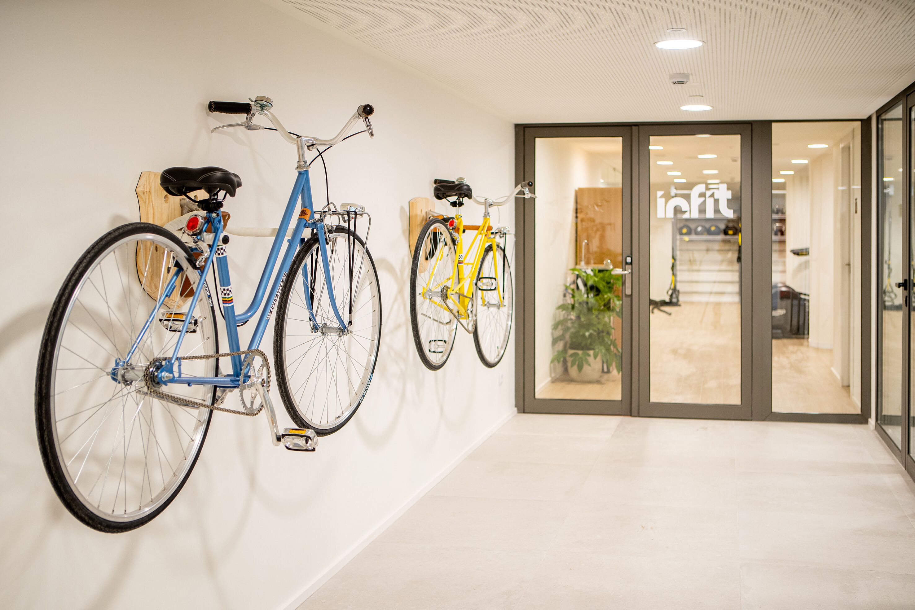 Een gang met twee fietsen aan de muur en een glazen deur naar een kamer.