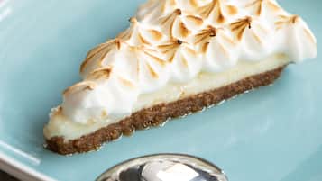 A slice of pie with a meringue topping on a light blue plate.
