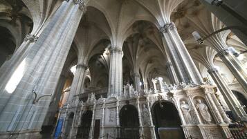 L’intérieur d’une cathédrale, avec de hauts plafonds en voûte, des colonnes richement décorées et des sculptures détaillées.