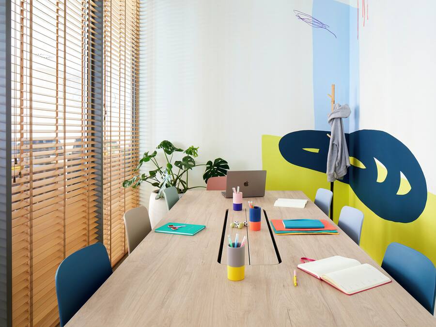 Une salle de conférence équipée d’une table en bois, de chaises, d’un ordinateur portable et de divers articles de papeterie.