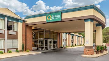 A hotel entrance with a sign reading "Quality Inn & Suites," featuring a brick facade, large windows, and a covered entrance area.
