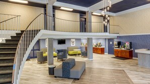 A spacious lobby with a staircase, seating area, and a reception desk.