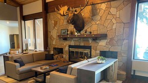 A cozy living room with a stone fireplace, a mounted moose head, and a modern sofa set. - Best Western Lake Lucille Inn (Wasilla)