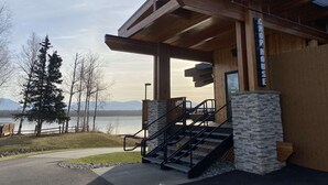 A wooden building with a stone base, labeled "CHOPHOUSE," featuring a staircase and a view of a lake and mountains. - Best Western Lake Lucille Inn (Wasilla)