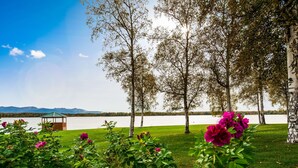 A lakeside view with birch trees, a gazebo, and vibrant flowers. - Best Western Lake Lucille Inn (Wasilla)