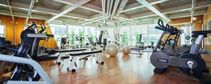Una palestra con macchinari cardio, attrezzatura per sollevamento pesi e palle da ginnastica.