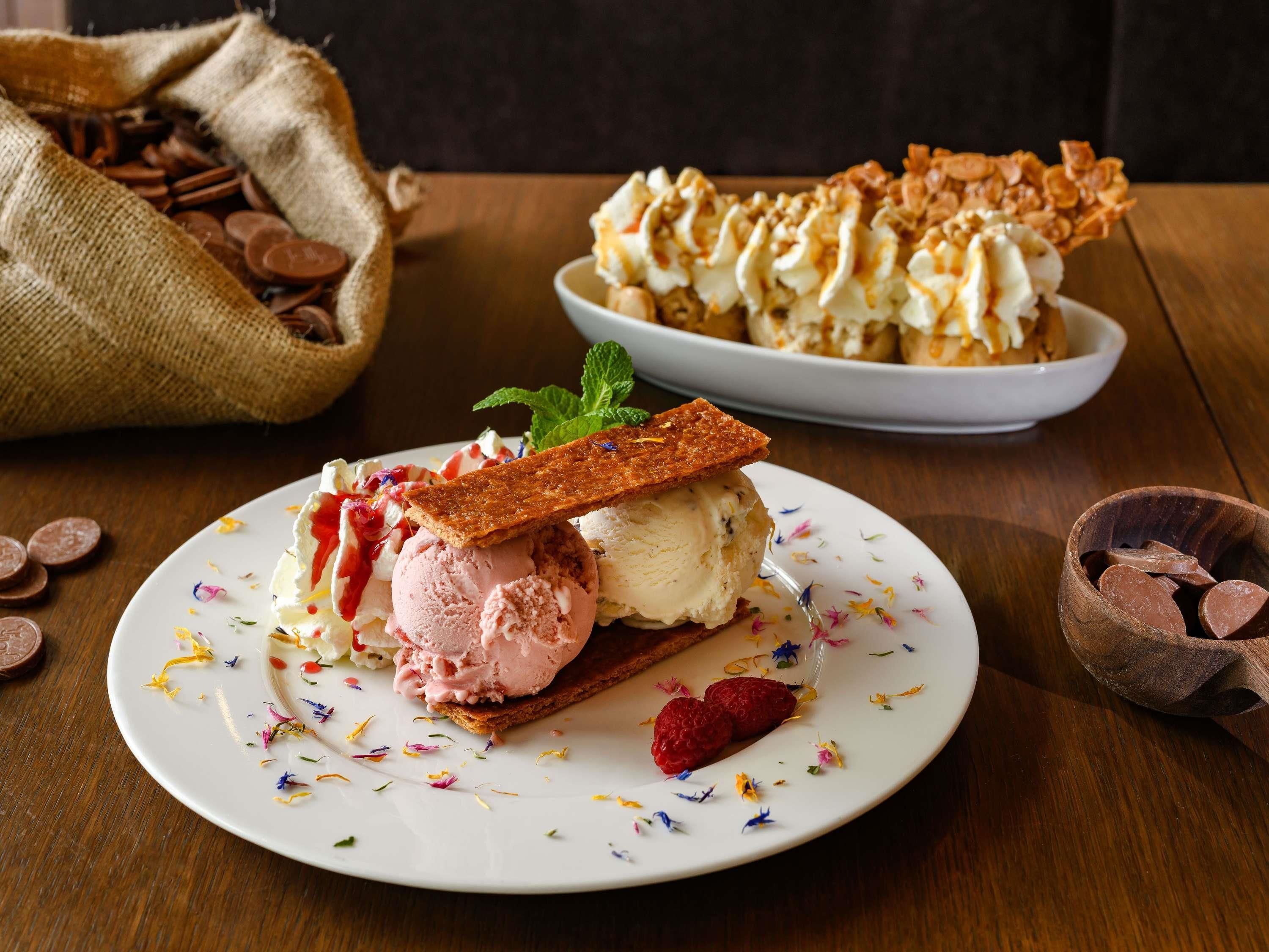 A dessert plate with ice cream and a piece of cake, a bowl of chocolate coins, and a burlap sack with more chocolate coins.