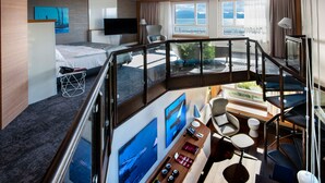 Una habitación de hotel moderna con balcón, cama, escritorio y televisor.