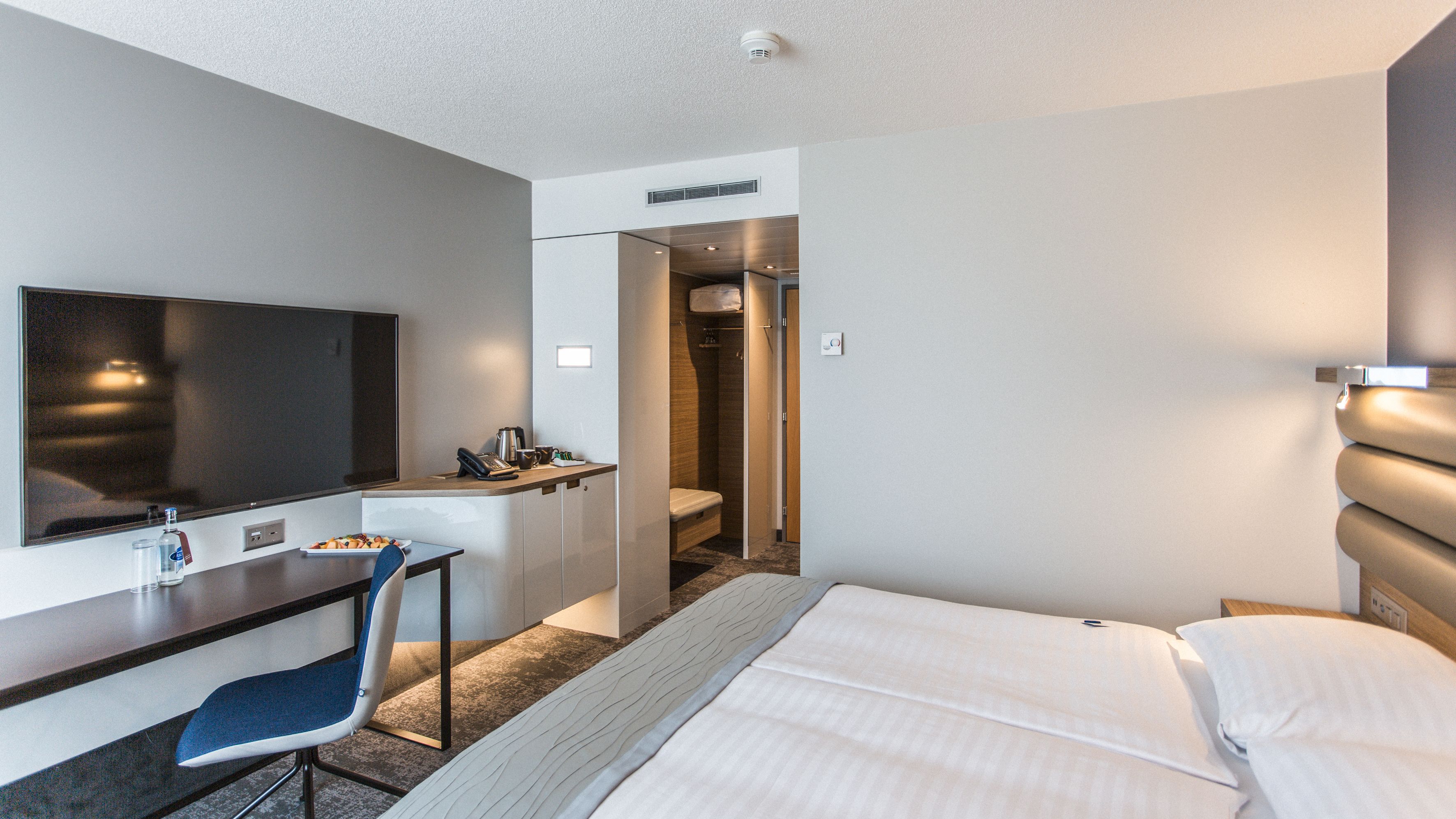 Une chambre d’hôtel équipée d’un lit, d’un bureau, d’une chaise, d’une télévision, d’une douche et de toilettes.
