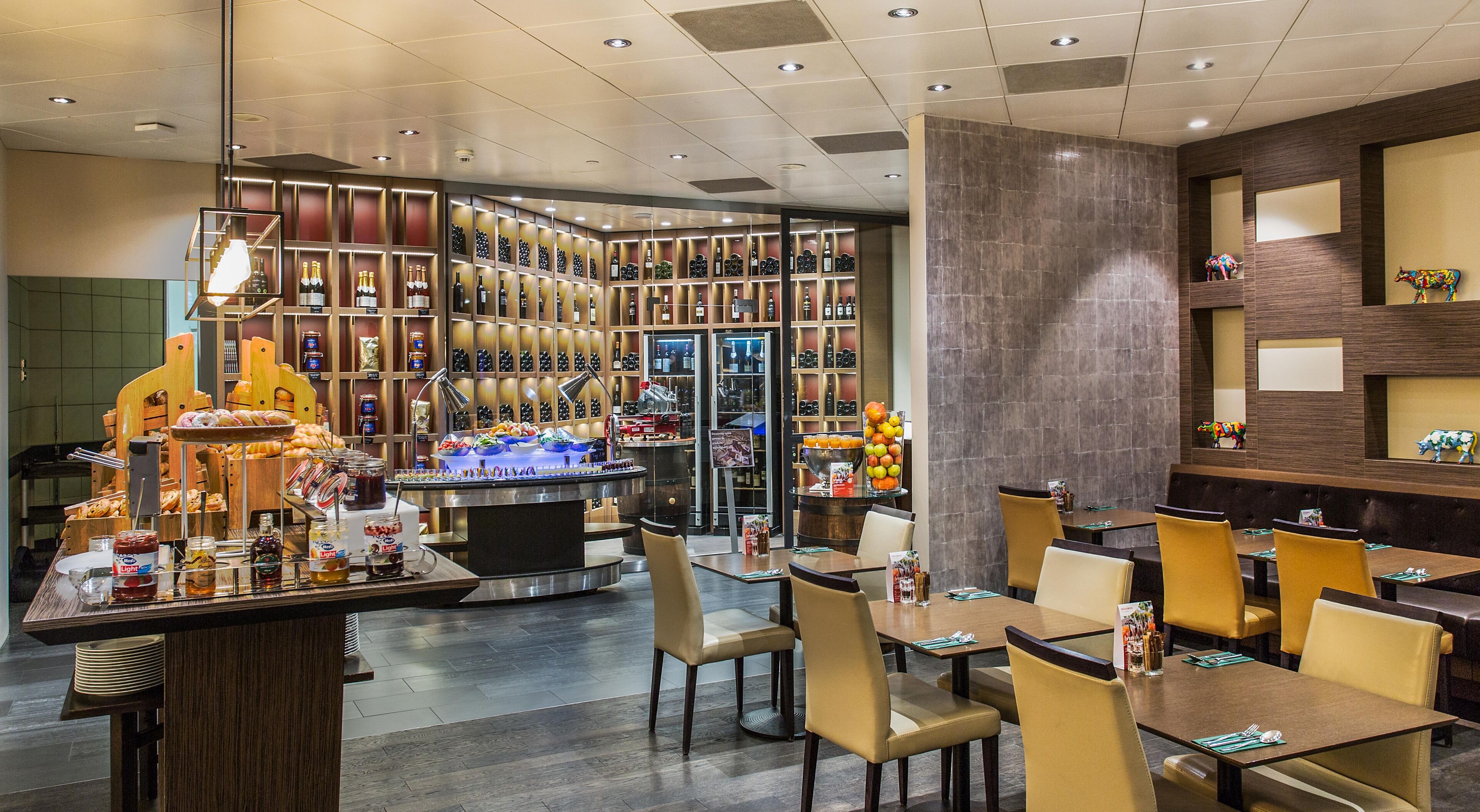 Een restaurant met een bar, zitplaatsen en een wijnkast.