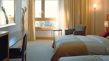 Una habitación de hotel con una cama, un escritorio, una silla, una mesita y una lámpara.