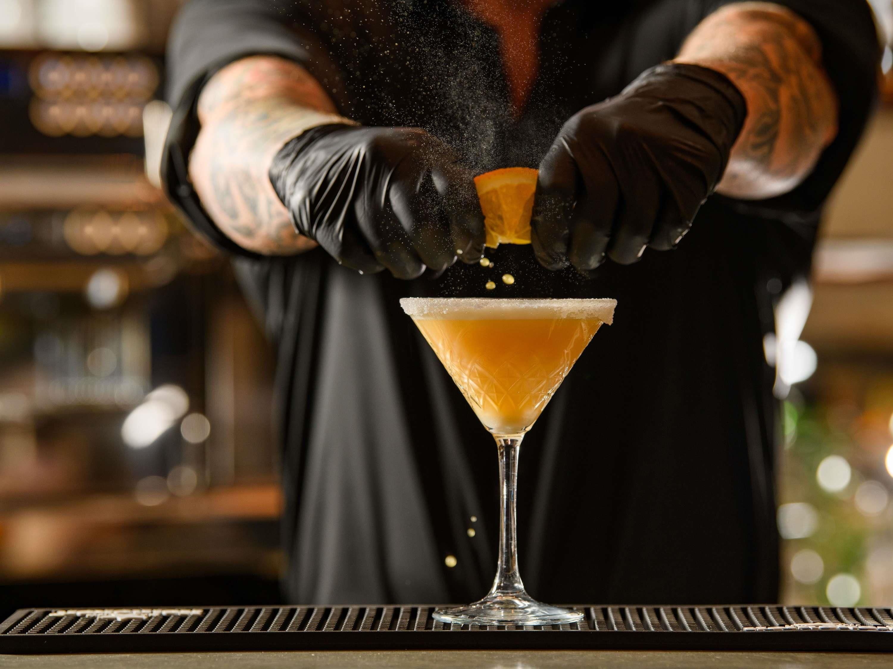 Een barman giet een drankje in een martini-glas.