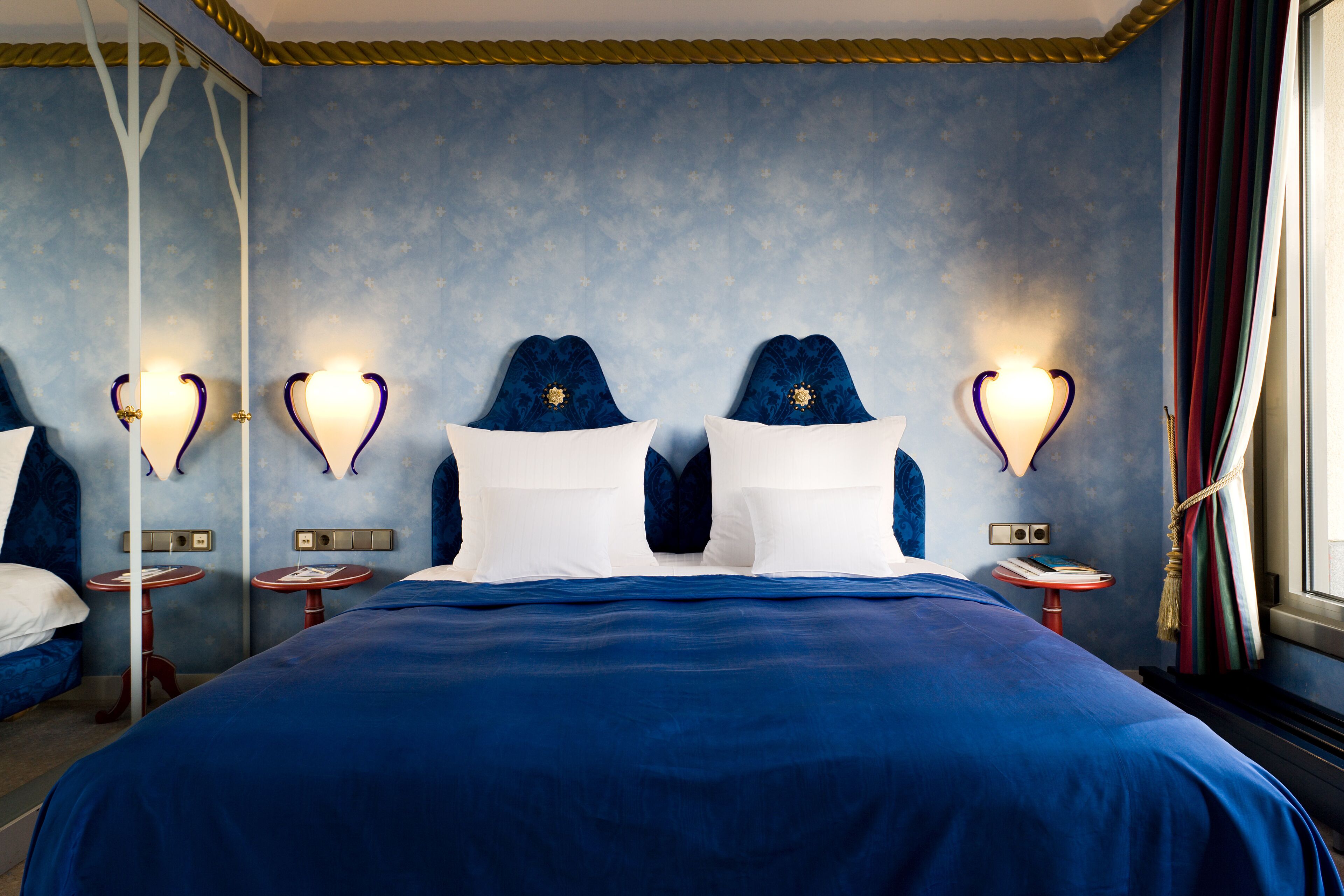 A hotel room with a large bed, two bedside tables, and a mirror.