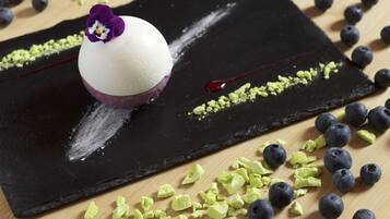 Postre sobre una losa de pizarra negra con arándanos y nueces verdes trituradas alrededor.
