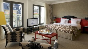Habitació d'hotel amb llit, televisió, taula de cafè i esmorzar, i vistes al balcó.