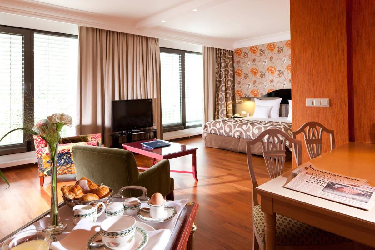 Een hotelkamer met een eethoek, een bed, een televisie en uitzicht op het omliggende landschap.