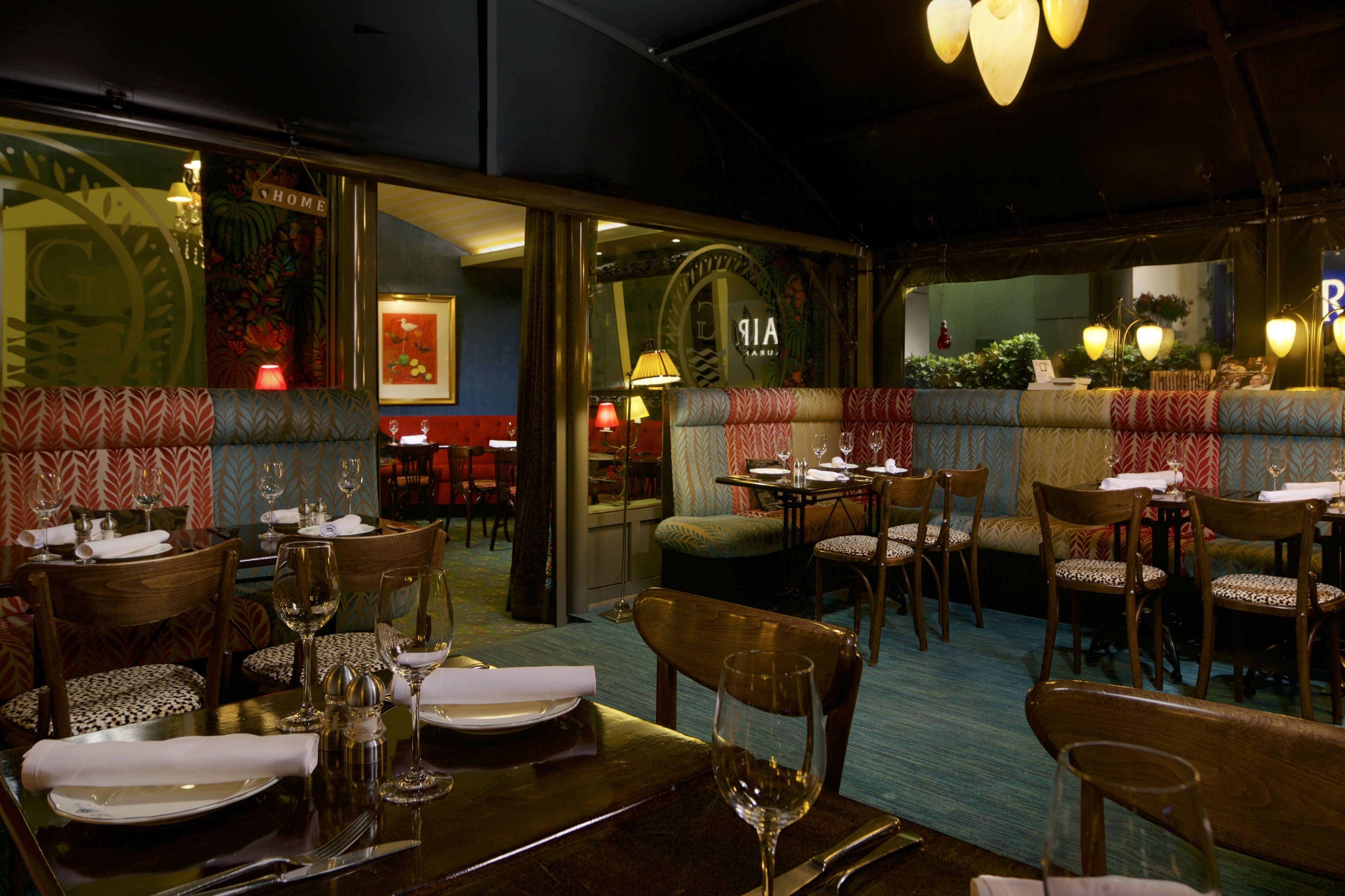 A restaurant with booths, tables, and chairs, some with patterned upholstery.