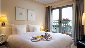 Habitació d'hotel amb un llit gran, una bandeja amb articles per esmorzar, un balcó amb vistes i una cadira.