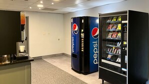 Un espace équipé de distributeurs automatiques de boissons Pepsi et FUSO, d’une machine à café et d’un sol carrelé.
