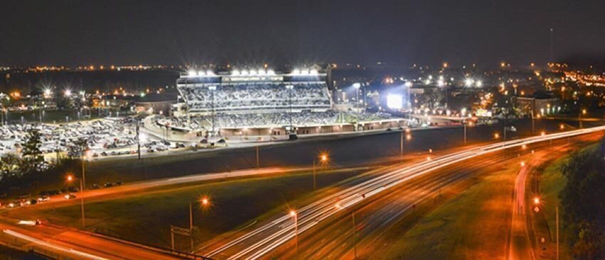 A large stadium with multiple tiers of seating, surrounded by parking areas and roads.