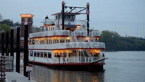 Un bateau fluvial à plusieurs ponts, doté d’un pont supérieur couvert, d’un pont inférieur avec un espace bar et d’une tour imposante.