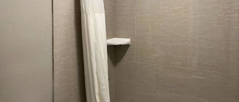 A bathroom with a shower curtain, a toilet, and a white bathtub.