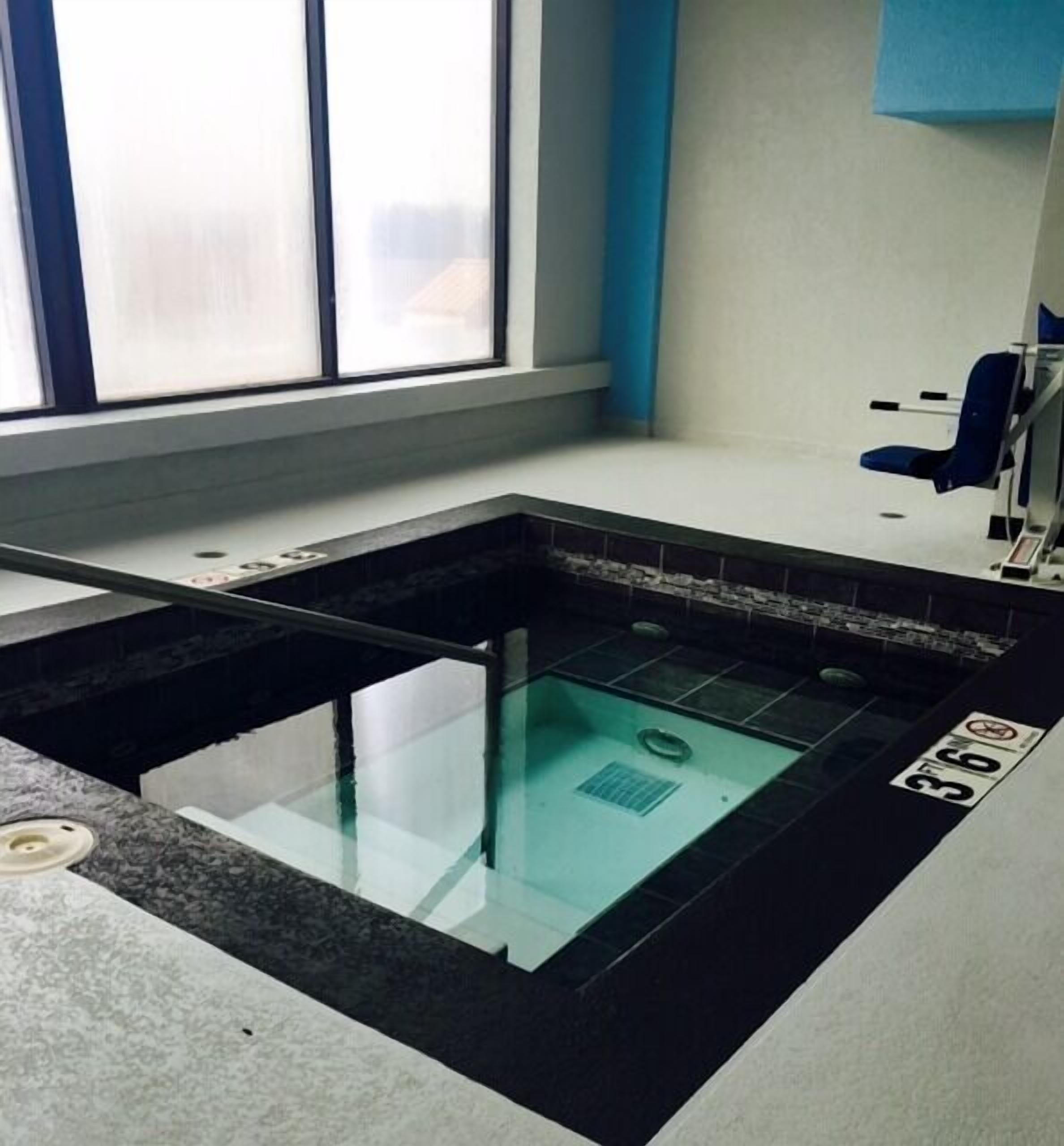 Ein Wellnessbereich mit einem gläsernen Whirlpool, einem blauen Stuhl und einem Schild, das eine Entspannungsbehandlung von 36 Minuten anzeigt.