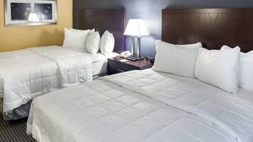 Una habitación de hotel con dos camas, una mesita de noche con lámpara y un cuadro enmarcado en la pared.