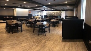 Un restaurant spacieux doté d’un plancher en bois et comprenant de nombreuses tables et chaises.