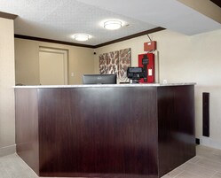 Un mostrador de recepción con una computadora portátil, un teléfono y un interfón de seguridad en el vestíbulo de un hotel.