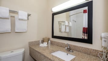 Un baño con encimera de granito, lavamanos, inodoro, perchero para toallas, espejo y secador de pelo.