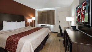 A hotel room with a large bed, a desk with a TV, a lamp, and a window with curtains. - Red Roof Inn Dayton - Huber Heights (Dayton)