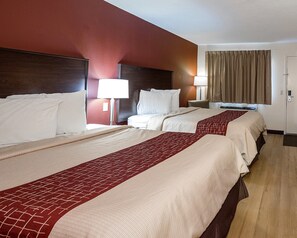 A hotel room with two beds, a nightstand, a lamp, a window with curtains, and a door. - Red Roof Inn Dayton - Huber Heights (Dayton)