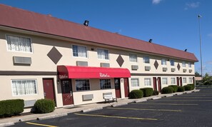 Un Red Roof Inn con toldo rojo, varias ventanas y un estacionamiento.