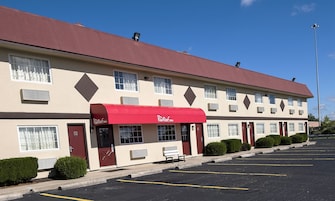 Un Red Roof Inn con toldo rojo, varias ventanas y un estacionamiento.