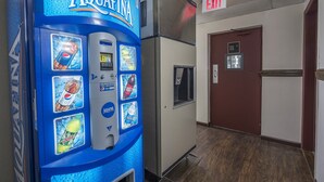 A vending machine with various drink options, an exit sign, and a door with a stairway sign.