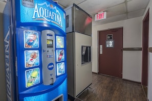 A vending machine with various drink options, an exit sign, and a door with a stairway sign. - Red Roof Inn Dayton - Huber Heights (Dayton)