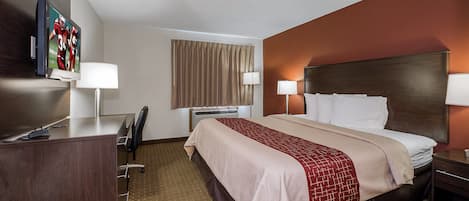 Une chambre d’hôtel comprenant un lit, des lampes de chevet, un bureau avec une chaise, une télévision et une fenêtre avec des rideaux.
